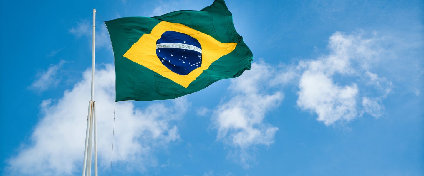Brazilian flag waving against a clear blue sky