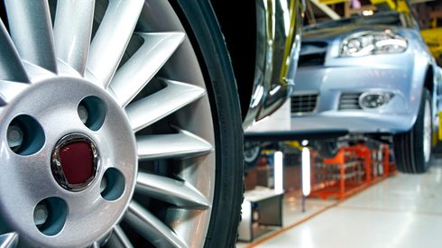 close up of car wheel in automobile manufacturing factory assembly line, USA