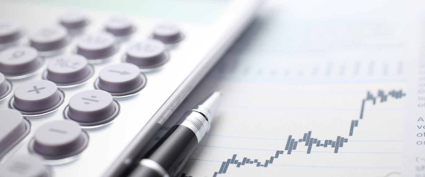 Calculator and ballpoint pen on stock market data chart