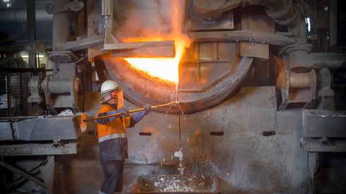 Worker taking sample from furnace in aluminium recycling plant