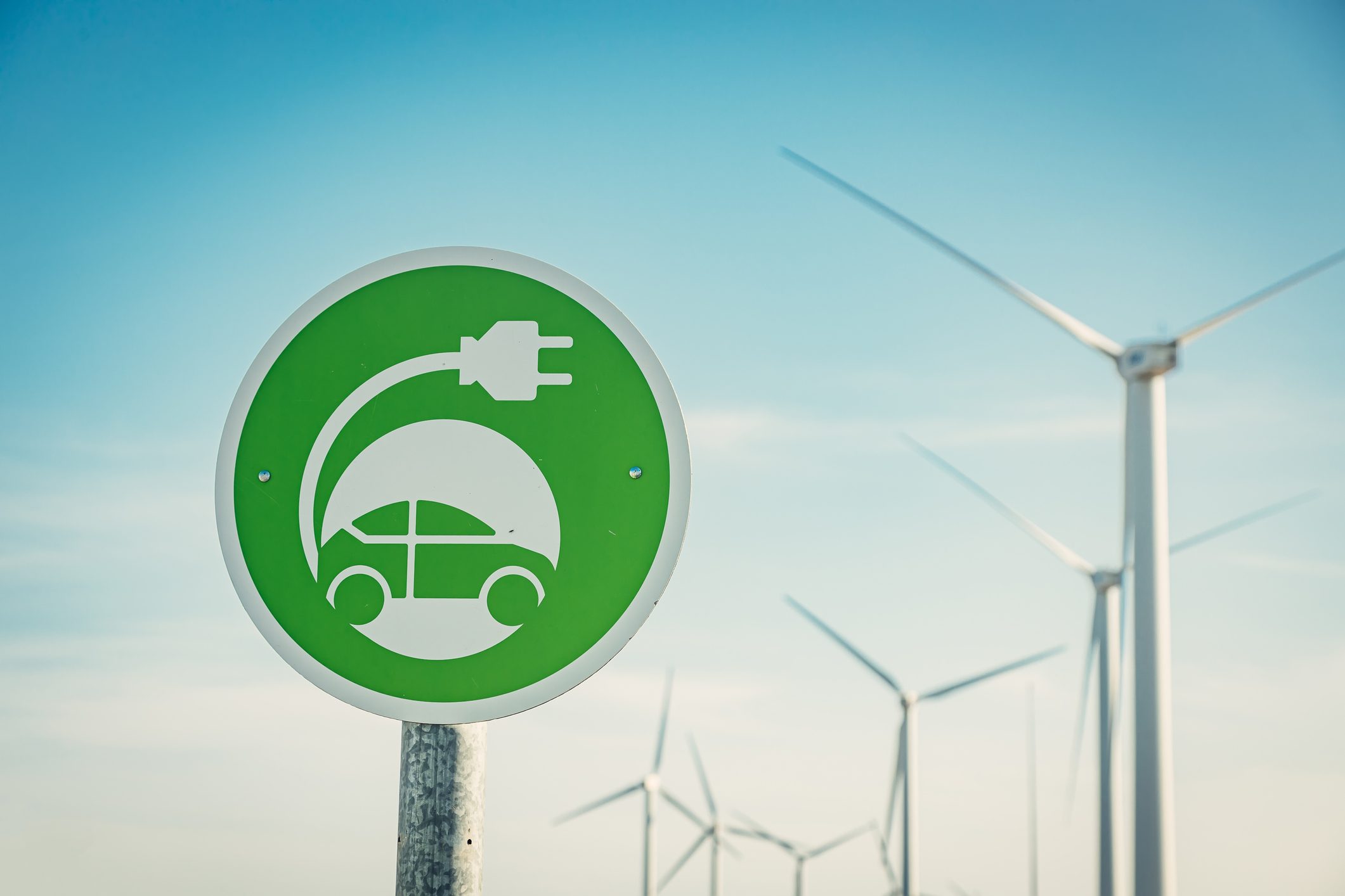 Electric car charge sign with wind turbines on background